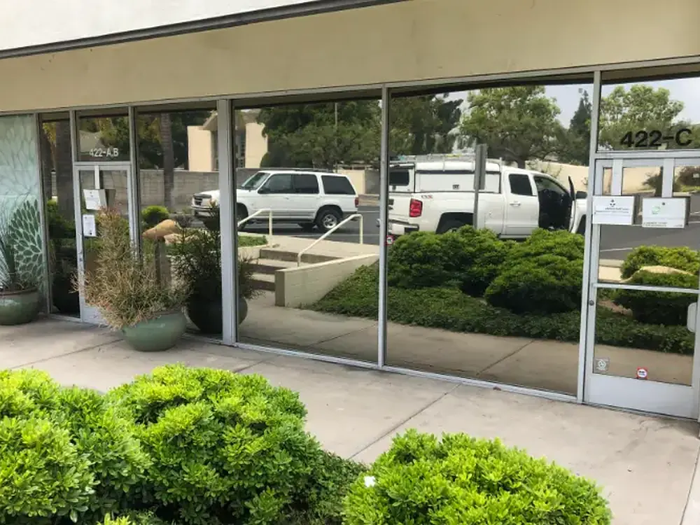 Storefront glazing carrying mirrored solar film under overcast light.
