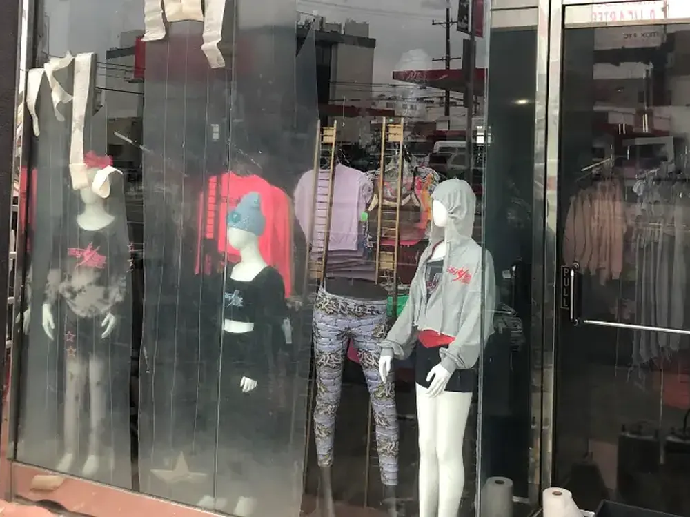 Hazed and scratched storefront glass in front of a clothing display, etched by repeated tagging.