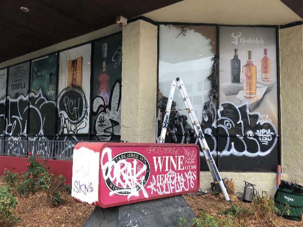 Graffiti across a full run of storefront glass before the anti-graffiti film went on.